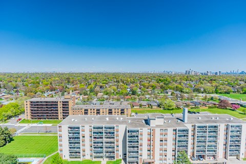 an aerial view of an apartment complex with trees and a city in the background